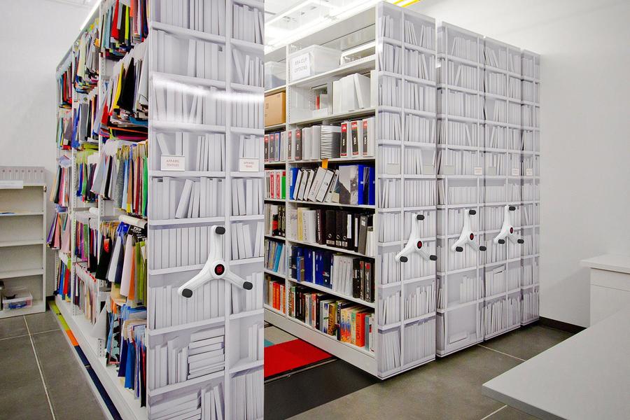 High-density mobile shelving in an office space, filled with folders and documents, optimizing storage.