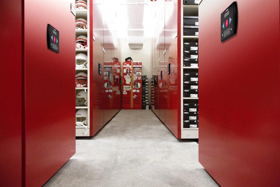 Mobile storage room for football equipment with red shelving.