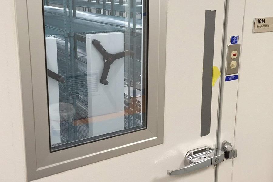 View through a window showing the mobile shelving mechanism in a secure storage room.