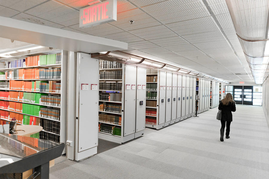 Estanter&#237;as m&#243;viles en una biblioteca con se&#241;alizaci&#243;n de salida.