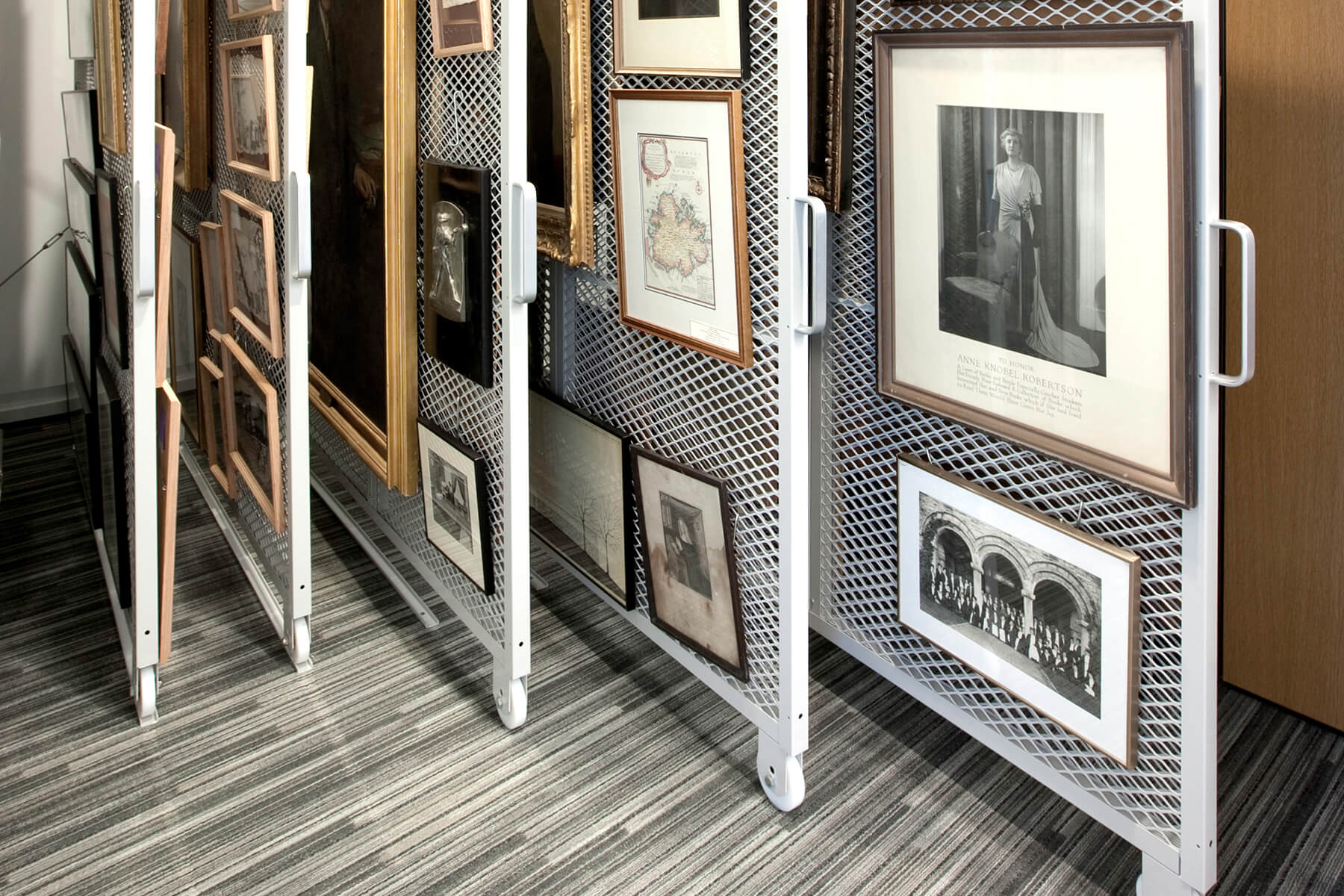 Mobile white shelving with framed artworks, allowing for efficient display and storage.