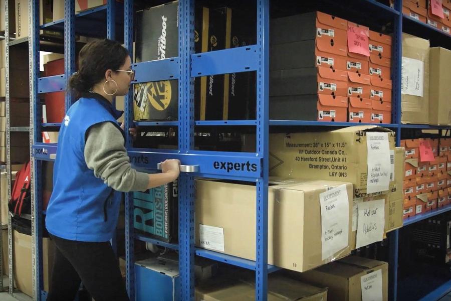 Worker handling items on blue shelving.