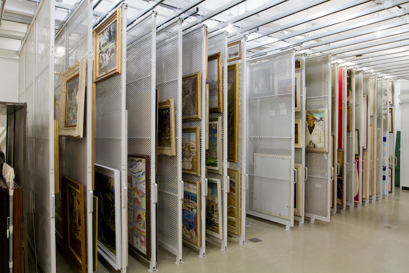 Mobile white shelving containing various framed artworks, illustrating an effective storage method.