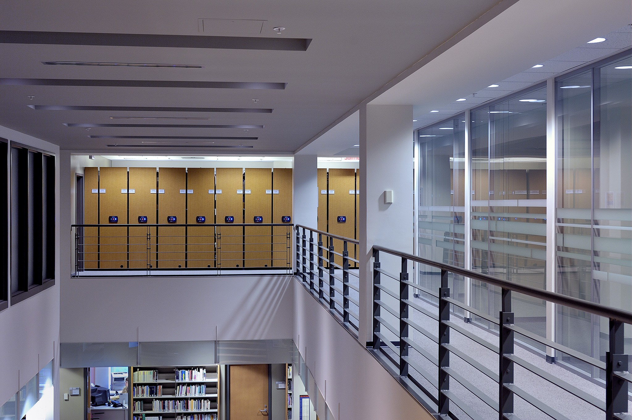 View of a hallway with lockers on the upper level and glass walls.