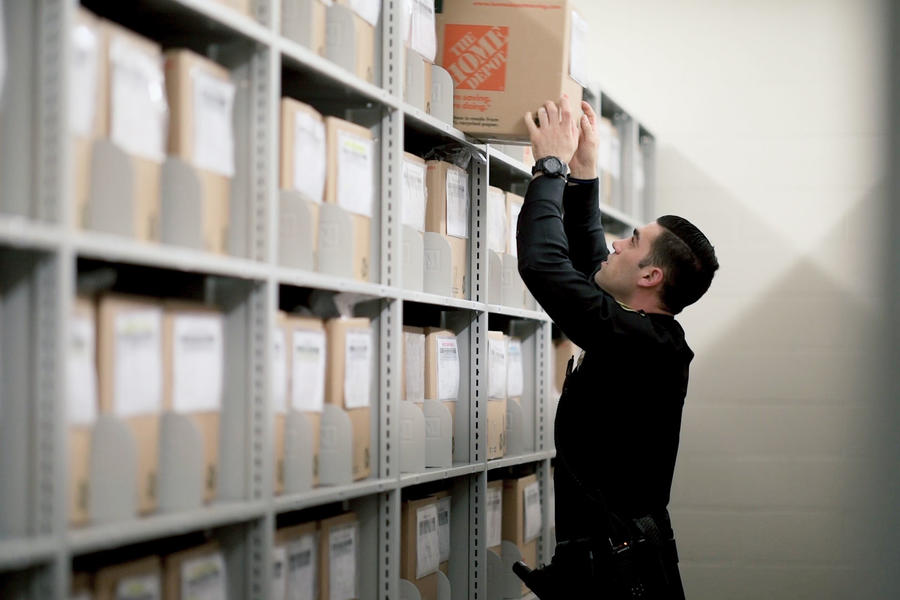 Officer organizing files in archive shelves.