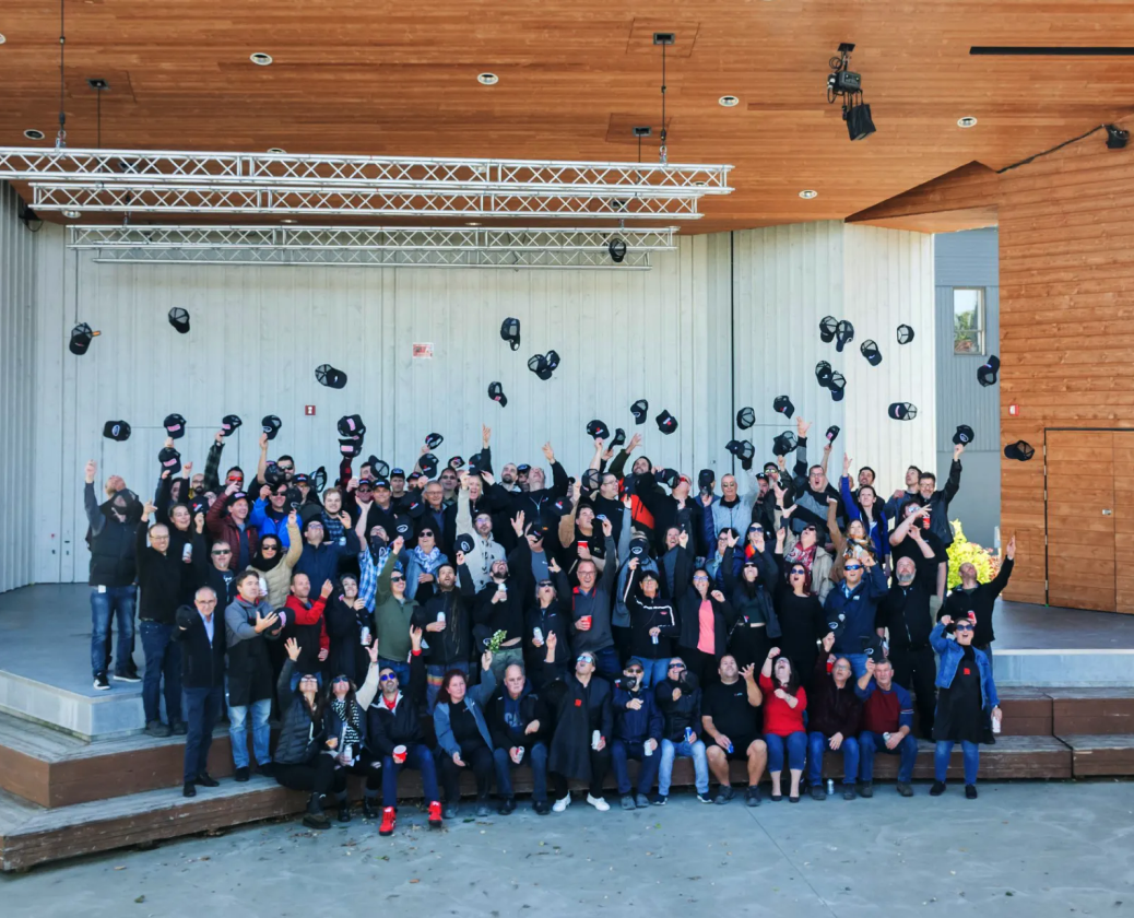 Montel team at an event, all raising caps in the air.