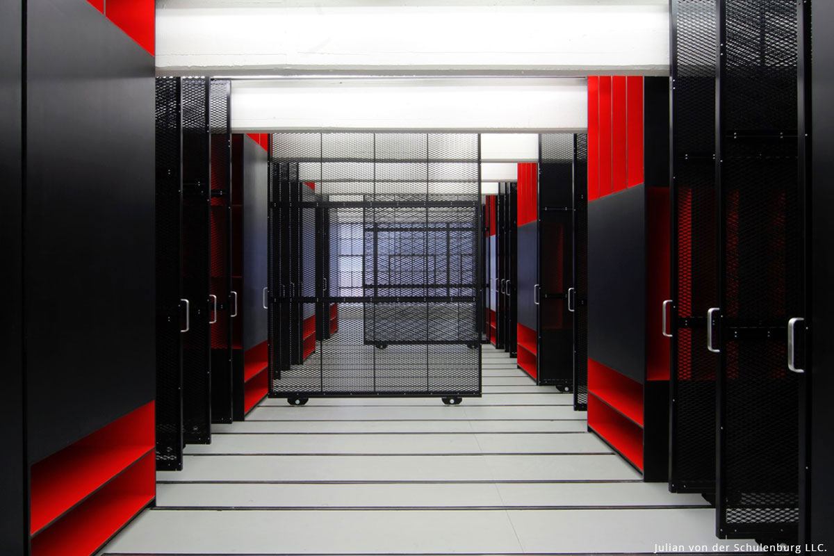 View of a storage corridor with black shelving, red accents, and modern lighting, creating an artistic atmosphere.