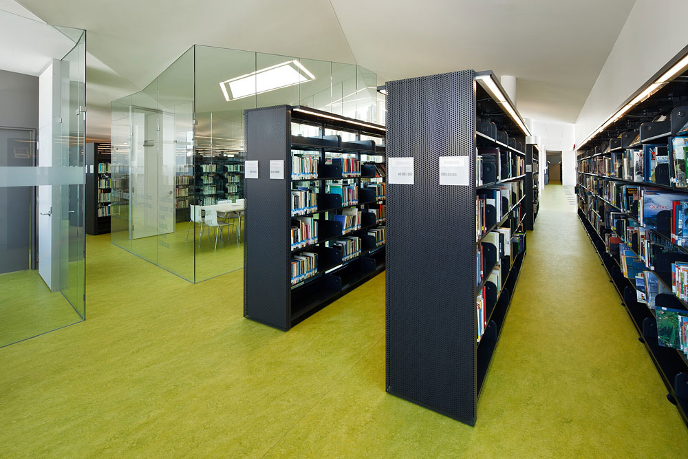 Row of black library shelves in a modern space with green flooring.