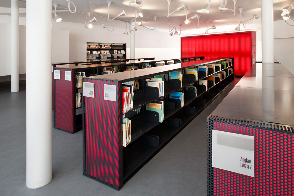 Library with red shelves and colorful books in a modern reading room.