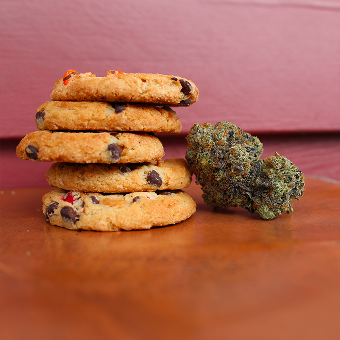 Stack of chocolate chip cookies next to a cannabis bud.