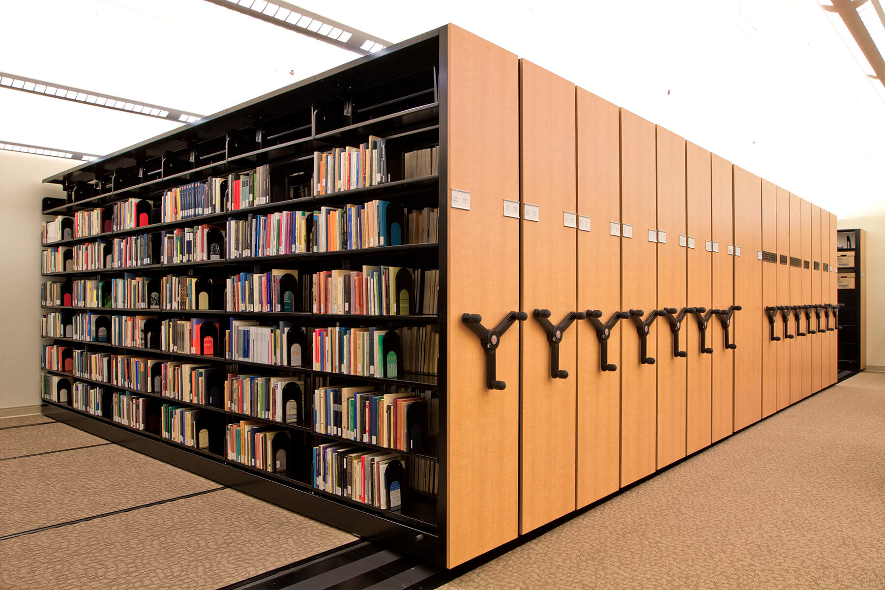 Mobile library shelves with light wood panels for space optimization.