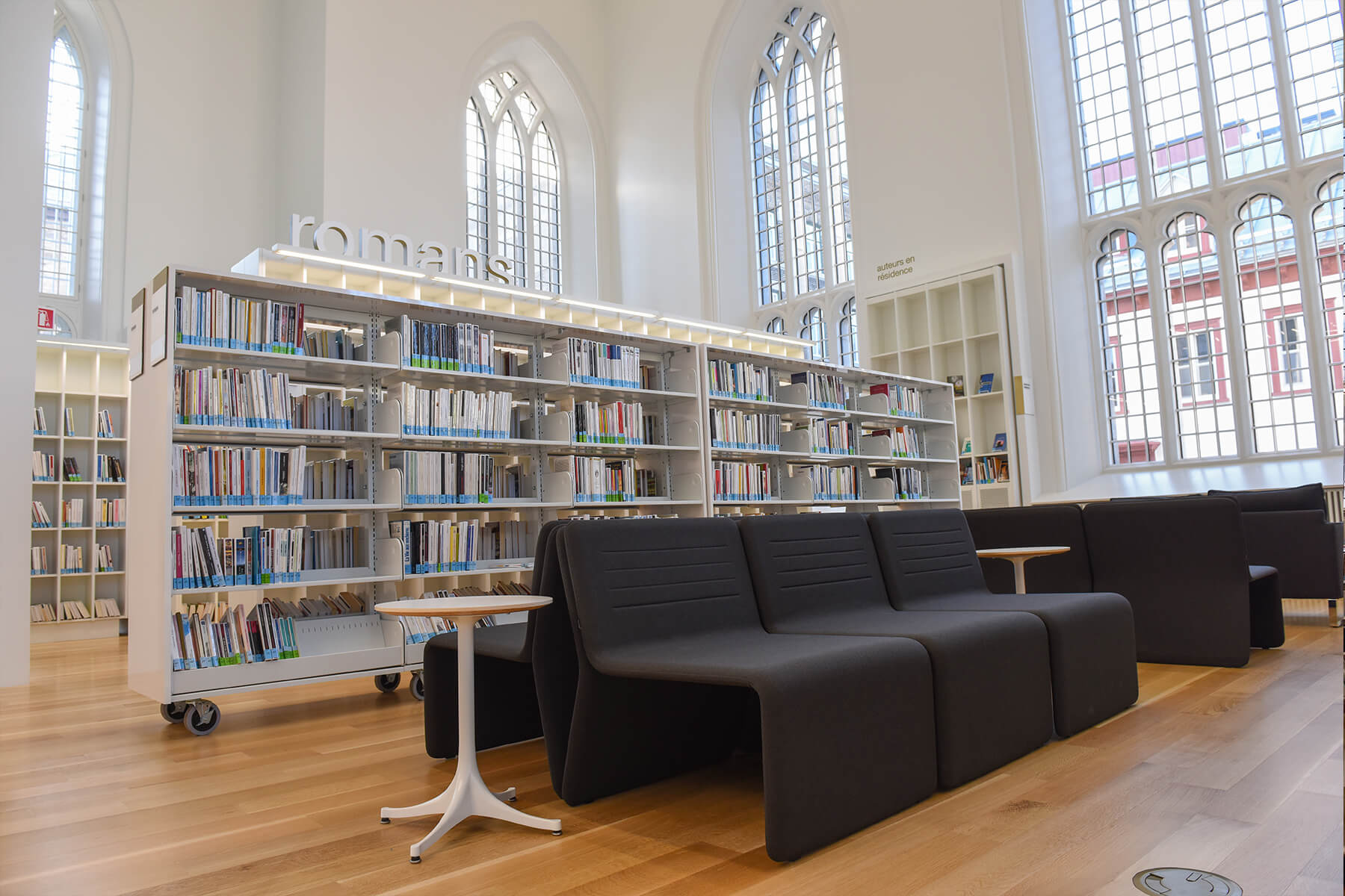 Cozy reading area with a black sofa and library shelves.