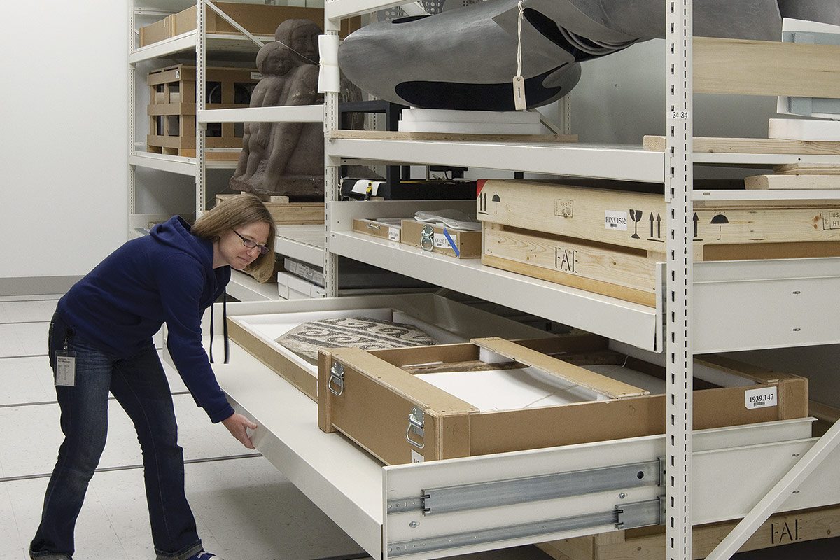 Une employ&#233;e examinant des tiroirs dans un espace de rangement, illustrant l&#39;utilisation de solutions de stockage modulaires.