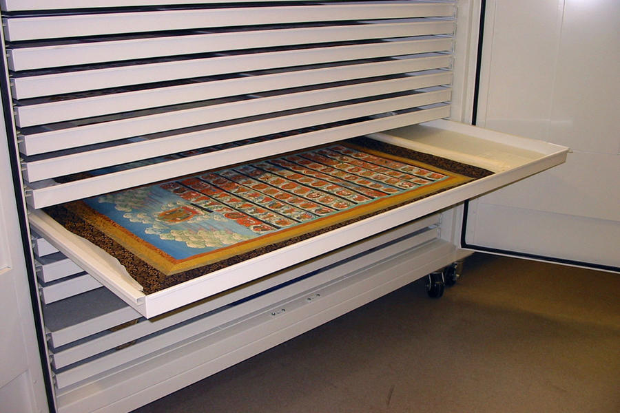 Drawer from a storage shelf containing a carefully placed colorful painting.