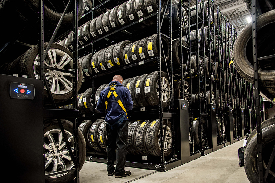 Employee checking tires on a black Montel shelving system designed for tire storage.